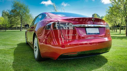 Red vintage car on grass against sky