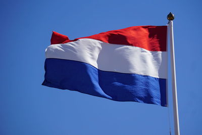 Low angle view of dutch flag waving against clear blue sky