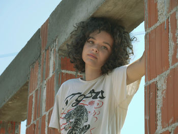 Portrait of teenage girl standing against wall