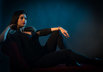 Woman looking away while sitting against wall