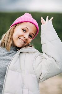 Portrait of smiling stylish teenage girl wearing pink fashion cap