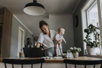 Multitasking mother taking care of baby and working from home