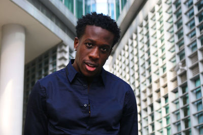 Portrait of young man standing against wall