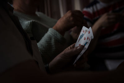 Midsection of people playing cards at home