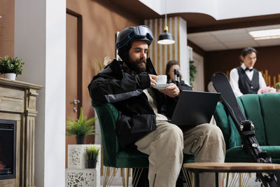 Young man using laptop while sitting on sofa at home