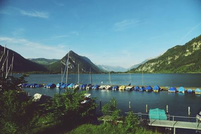 Boats moored in sea against blue sky