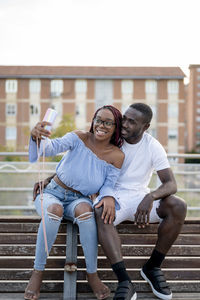 Smiling young couple taking selfie on bench