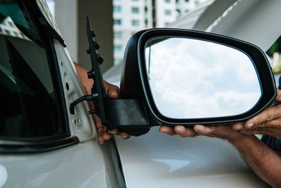 Reflection of man on side-view mirror of car