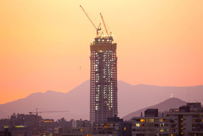 Illuminated buildings in city against sky during sunset