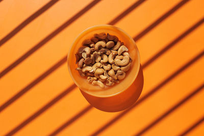 Top view of cashew nut in a bowl on orange background