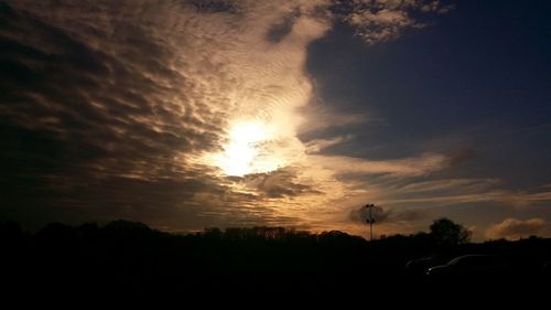 Sun shining through clouds over landscape