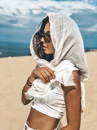 Young woman wearing sunglasses standing at beach