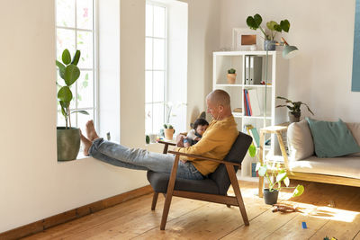 Men sitting on potted plant at home