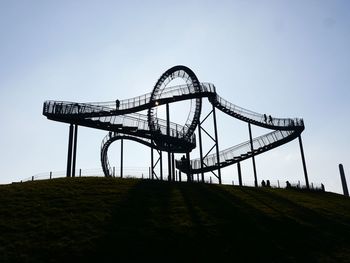 Low angle view of silhouette rollercoaster against sky