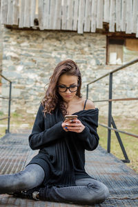 Young woman using mobile phone on footbridge