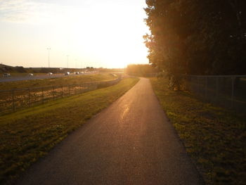 Road amidst trees against sky during sunset