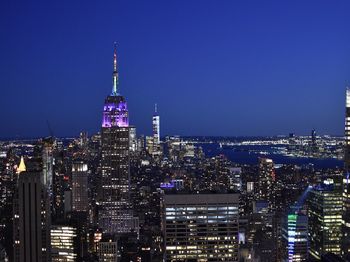 Illuminated buildings in city against blue sky