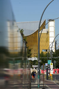 Man walking on road in city against sky