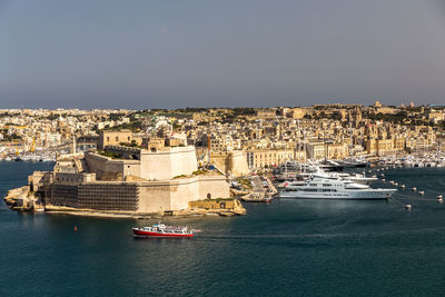 Boats in sea against buildings in city