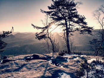 Rocky mountain with snow cover and the sun at horizon . blue sky background