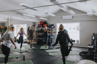 Group of people having stretching practice in gym