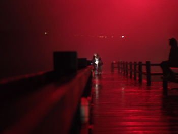 People walking on illuminated road against sky at night