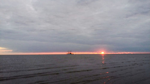 Scenic view of sea against cloudy sky during sunset