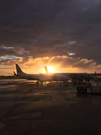 Silhouette airplane on runway against sky during sunset