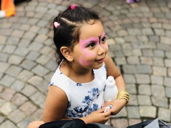 Portrait of cute girl sitting on footpath