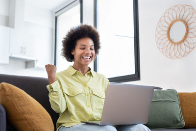 Young woman using laptop while sitting on sofa at home