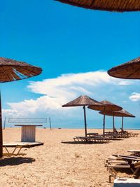 Deck chairs on beach against sky