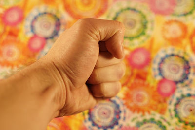 Cropped hand of man clenching fist against wall