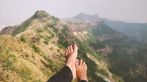 Low section of person on mountain against sky