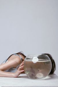 Midsection of woman holding glass against white background