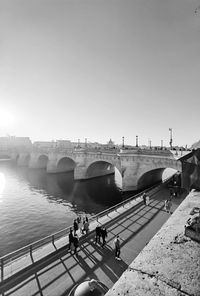 People on bridge over river against sky