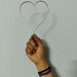 Close-up of hand holding heart shape against white background