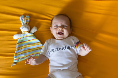 Cute smiling baby lying on bed at home