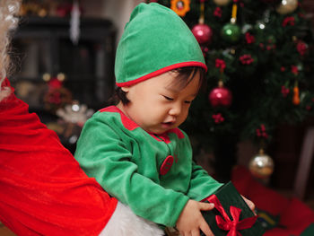 Close-up of baby girl and santa claus with christmas gift at home