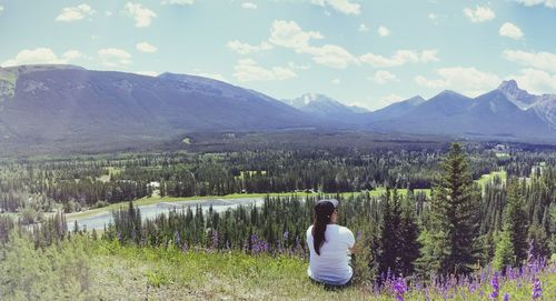 Rear view of woman standing on field against mountain