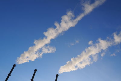 Low angle view of smoke stack against blue sky