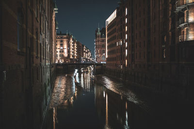 Canal amidst illuminated buildings in city at night