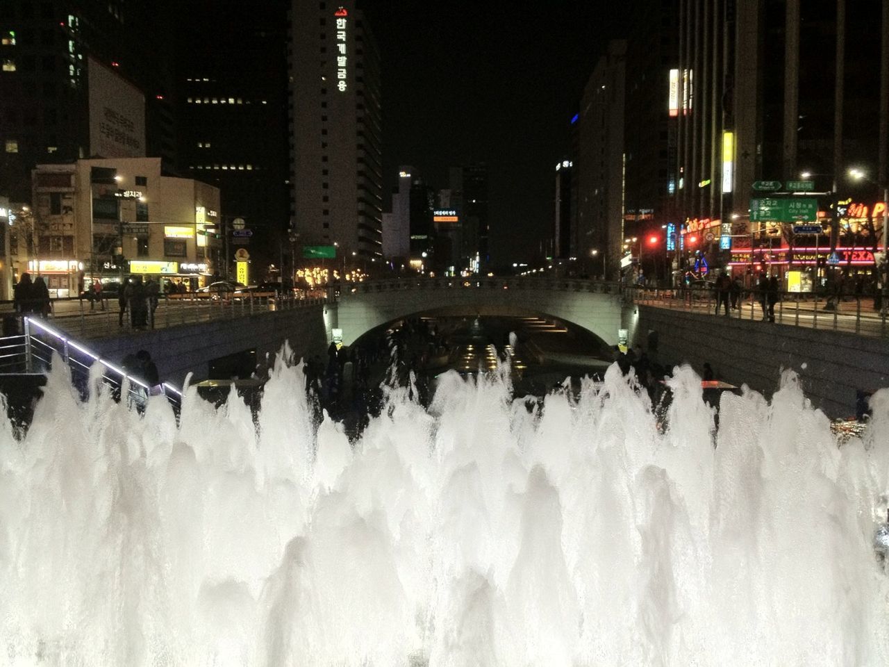 illuminated, night, building exterior, city, architecture, built structure, snow, winter, cold temperature, city life, street light, transportation, season, skyscraper, cityscape, outdoors, modern, white color, street, weather