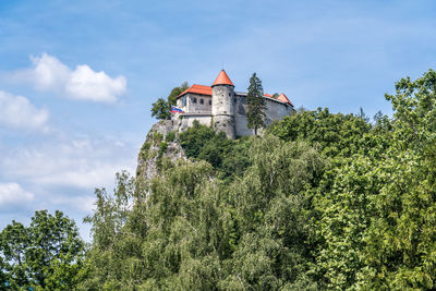 Low angle view of trees and building against sky