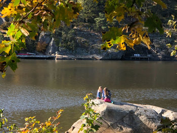 People sitting on rock by lake