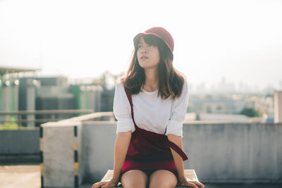 Young woman wearing hat sitting outdoors