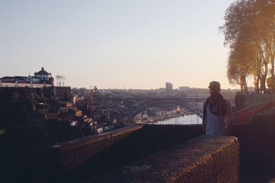 Rear view of man standing by buildings against clear sky