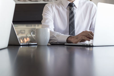 Rear view of man using laptop on table