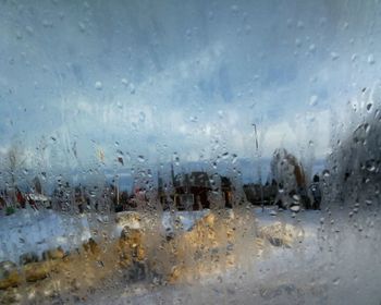 Close-up of wet window against sky