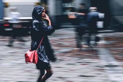 Blurred motion of woman walking on city street during rainy season