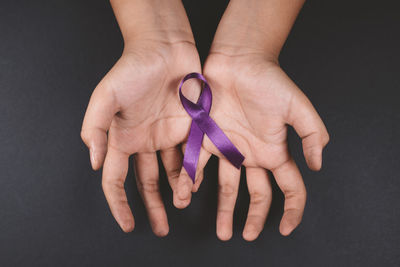 Midsection of woman holding purple against black background